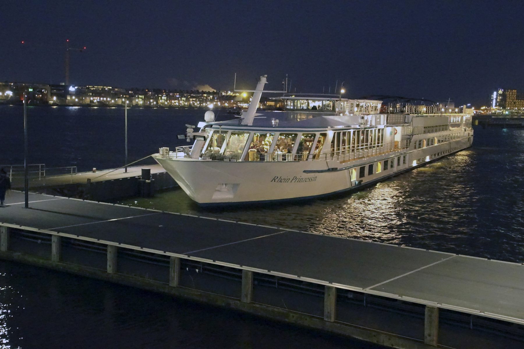 River cruise ship moored at a floating pontoon in Cologne at night